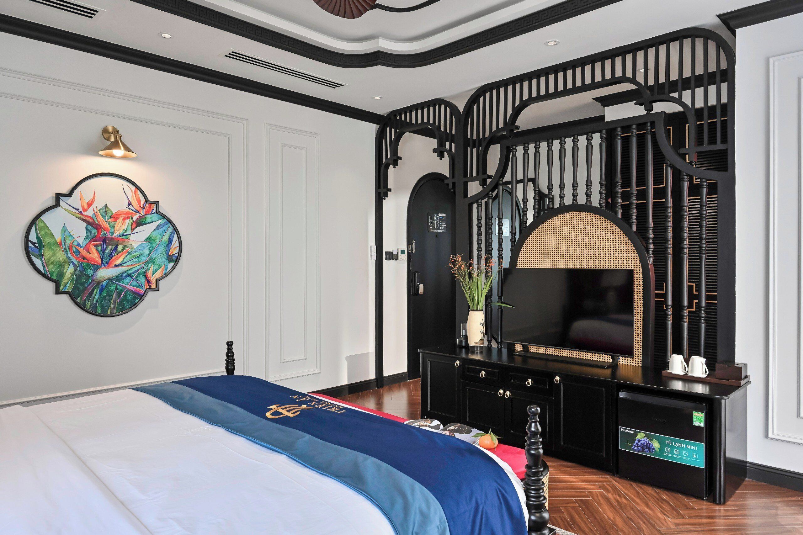 Ein Schlafzimmer mit Bett, Fernseher, einer Konsole und einer Wanddekoration.