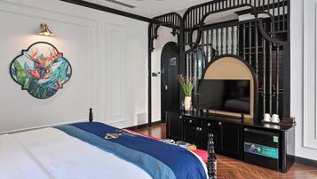 Ein Schlafzimmer mit Bett, Fernseher, einer Konsole und einer Wanddekoration.