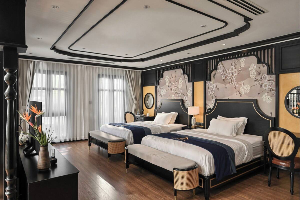 Habitación de hotel con dos camas, un escritorio con un florero y un mural floral grande.