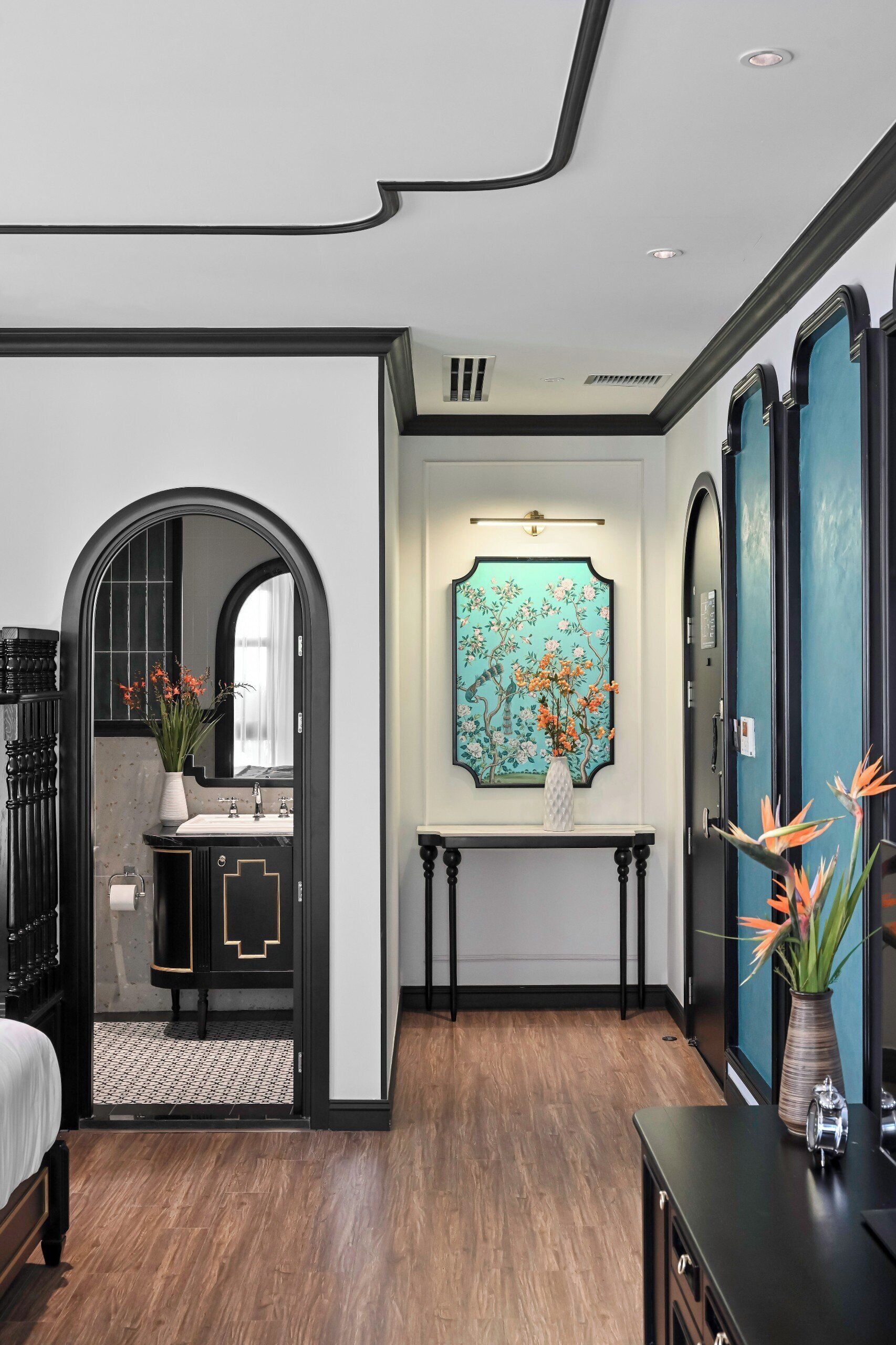 Un baño moderno con un tocador negro, un espejo y una obra de arte floral sobre el lavabo.