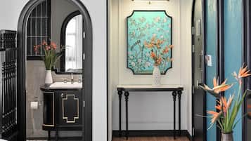 Un baño moderno con un tocador negro, un espejo y una obra de arte floral sobre el lavabo.