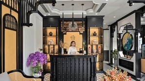 A reception desk with a receptionist, surrounded by decorative shelves and a large floral arrangement.