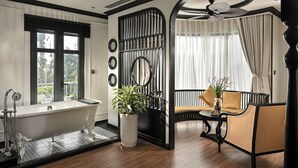 A bathroom with a freestanding bathtub, a potted plant, and a black-framed mirror.
