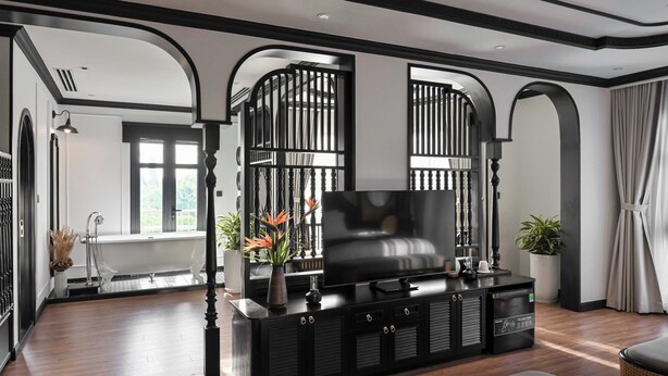 A modern living room with a black entertainment unit, a large flat-screen TV, and a staircase leading to another level.