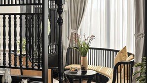 A room with a black and white color scheme, featuring a black sofa, a small table with a vase, and a black railing.
