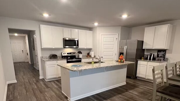 A modern kitchen with white cabinets, a central island, and a microwave above it. - Welcoming Spacious Crestview Home w/ Pool Access & Fire Pit (Crestview)