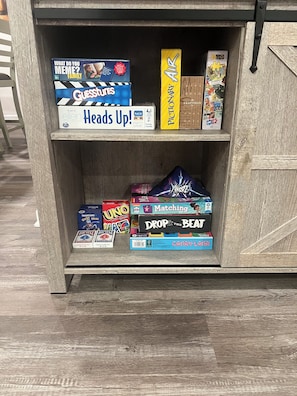 Una estantería de madera con varios juegos de mesa y rompecabezas.
