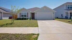 A residential building with a garage, a front lawn, and a clear sky. - Welcoming Spacious Crestview Home w/ Pool Access & Fire Pit (Crestview)