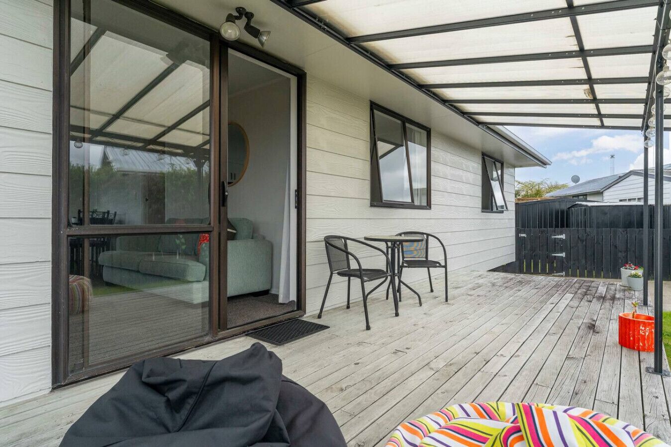 A covered patio with a sliding glass door, a small table, two chairs, and a colorful bean bag.