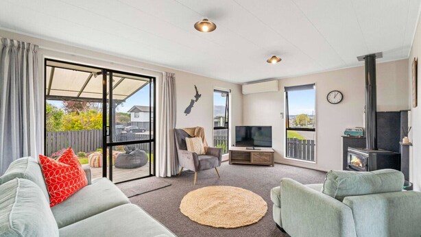 Ein modernes Wohnzimmer mit Sofa, Fernseher, Kamin und großen Fenstern.