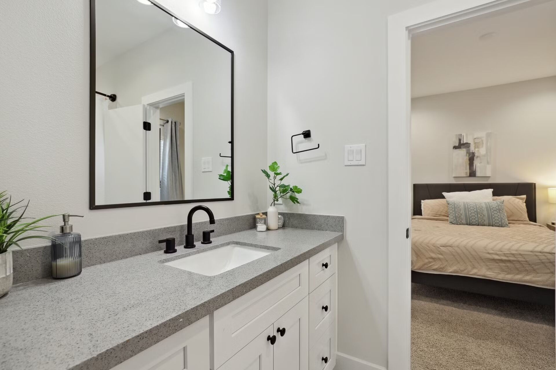 Un baño moderno con un espejo grande, un lavabo y una planta.