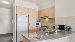 Una cocina moderna con armarios de madera, un refrigerador de acero inoxidable, un microondas, un horno y un lavamanos.