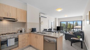 Una cocina moderna con lavavajillas, estufa y comedor con televisor y asientos.