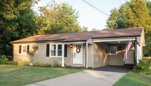 A single-story house with a front porch, a mailbox, and an American flag. - Modern 3-bedroom house near downtown Forest City with a private backyard. (Forest City)