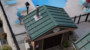 Ein Pool auf dem Dach mit blauen Liegestühlen, einem überdachten Sitzbereich und einem kleinen Gebäude mit grüner Dachbegrünung.