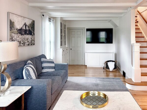 Una sala de estar con un sofá, una mesa de centro, una lámpara y un cuadro en la pared.