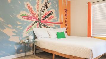 A bedroom with a bed, a nightstand, a wall mural, and a window with blinds.