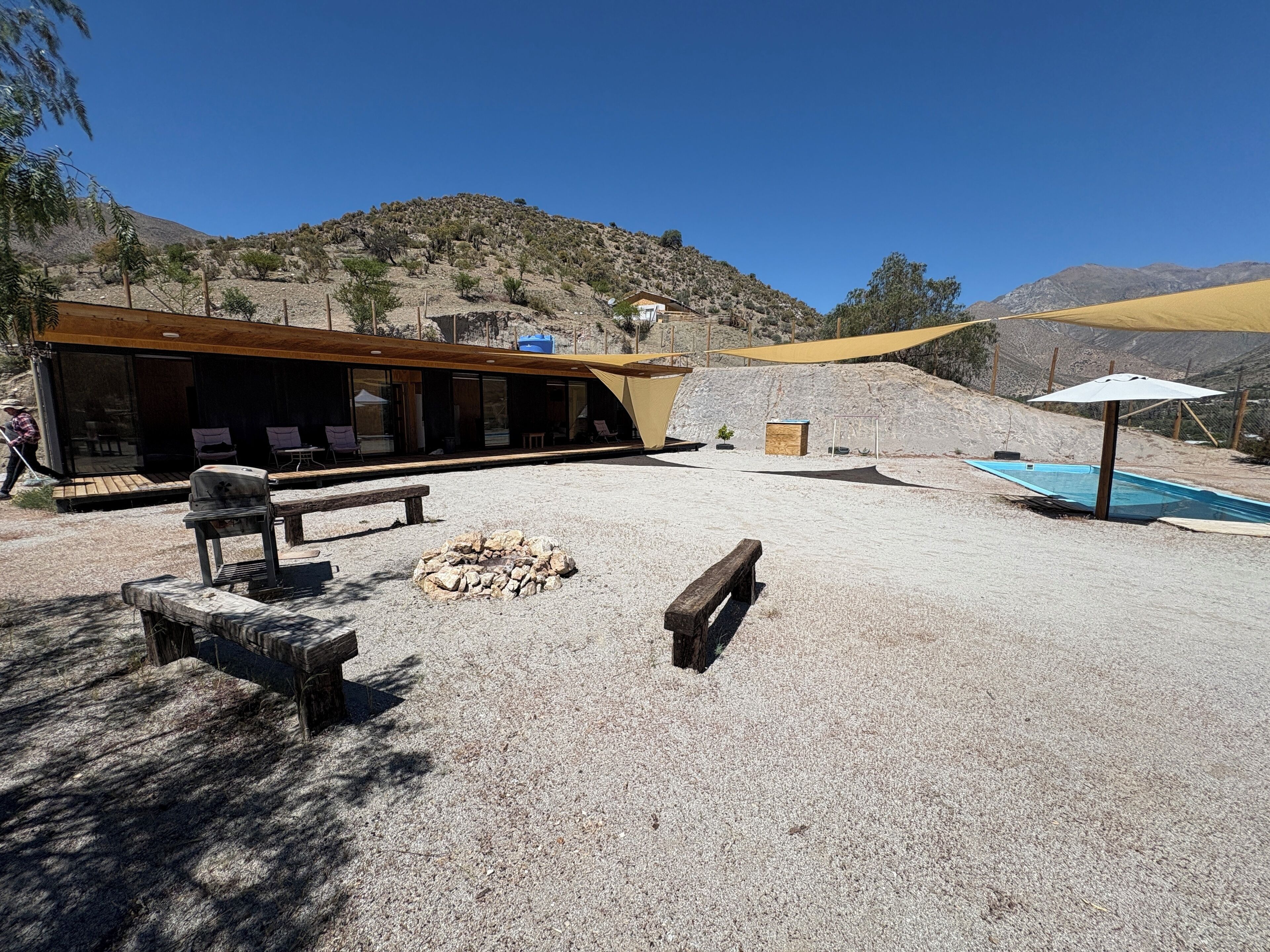 A modern outdoor area with a wooden deck, a fire pit, and a pool.