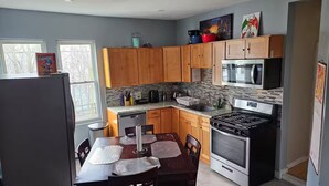 A compact kitchen with wooden cabinets, a microwave, a stove, and a dishwasher. - Lovely fully equipped 4-bedroom apartment in charming Boston with parking. (Boston)