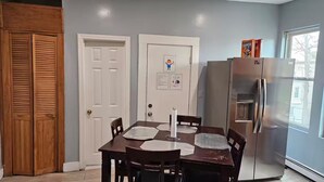 A dining area with a wooden table, chairs, a white door, and a stainless steel refrigerator. - Lovely fully equipped 4-bedroom apartment in charming Boston with parking. (Boston)