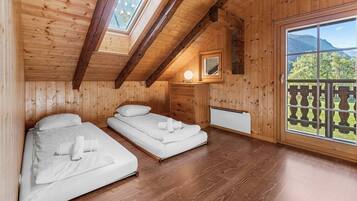 Ein gemütliches Holzhütten-Zimmer mit zwei Betten, einem Fenster und Blick auf einen Berg.