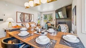 Un espace repas avec une table en bois dressée pour quatre personnes, entourée de sièges confortables.