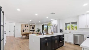 Uma cozinha moderna com uma ilha central, armários escuros e vista para o exterior.