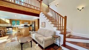 A spacious living area with a wooden staircase, a kitchen with wooden cabinets, and a dining area with a table and chairs.