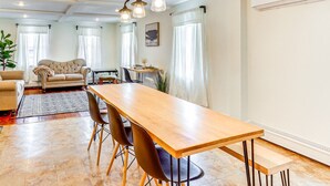 Un salón comedor amplio con una gran mesa de madera, un sofá color beige y una araña.