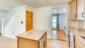 Una cocina con encimeras de granito, armarios de madera y una puerta de madera.