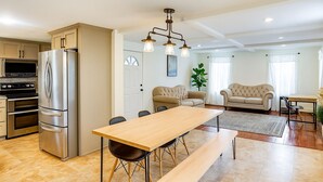 Una cocina moderna con electrodomésticos de acero inoxidable, una mesa de comedor de madera y un área de estar con dos sofás y una mesita de centro.