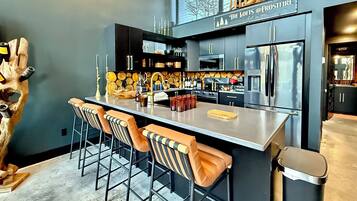 A modern kitchen with a bar area, stainless steel appliances, and a unique wooden sculpture.