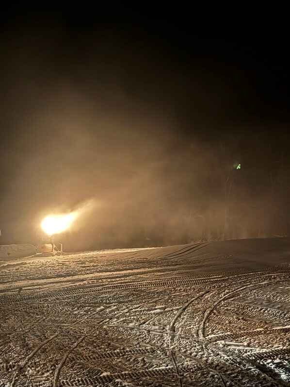 A snowy landscape with tire tracks and a distant light source.