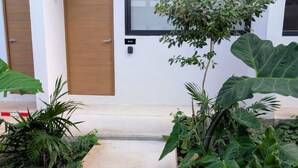 A modern building with a concrete pathway leading to a wooden door and a window. - Makech Montebello - By Kanaa (Mérida)