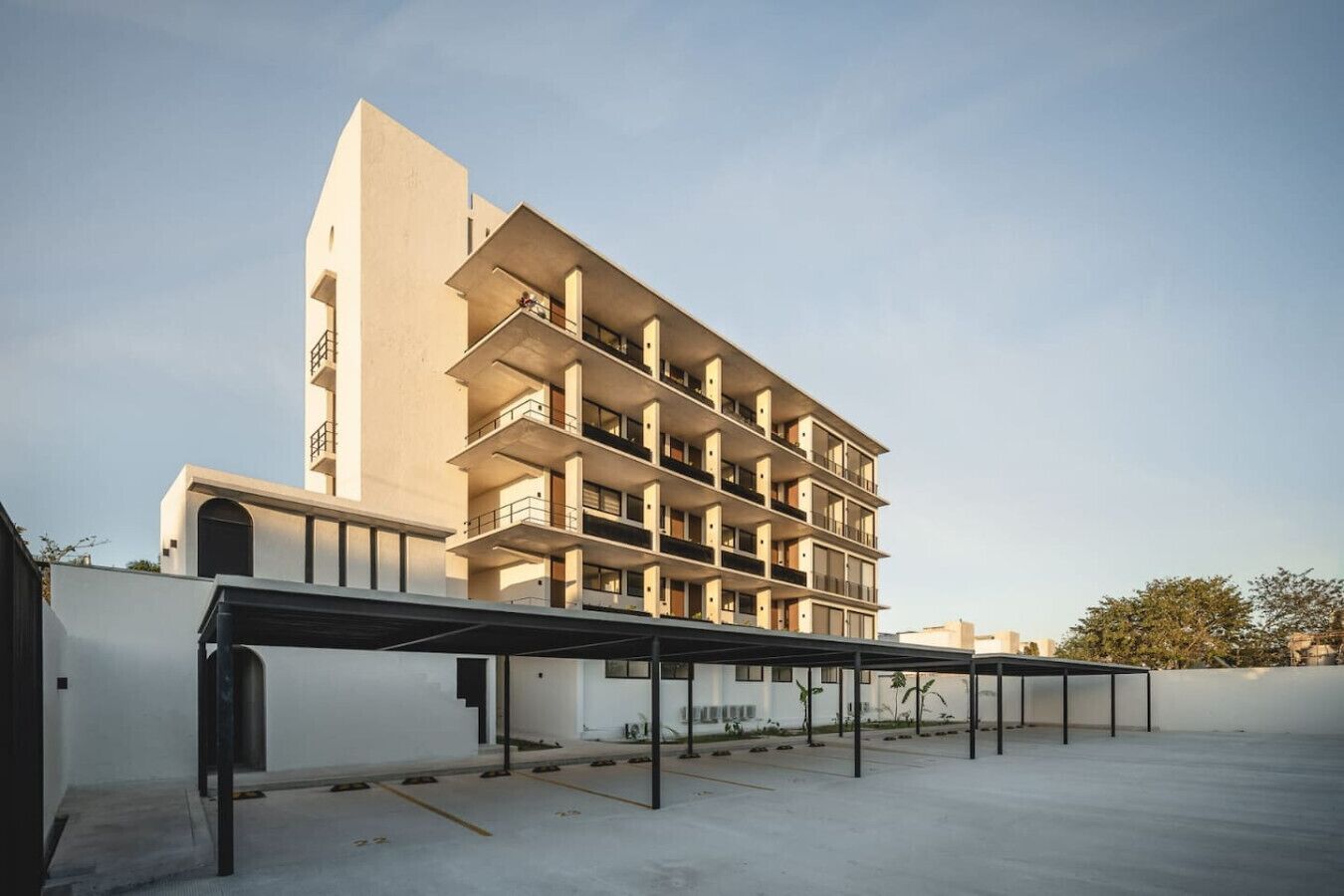 A multi-story hotel with a modern design, featuring balconies on each floor and a covered outdoor area.