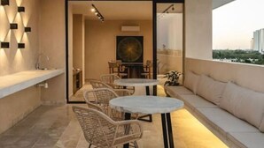 Een balkon buiten met een zithoek, een tafel en stoelen.