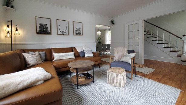 A living room with a brown leather sofa, a round coffee table, and a patterned rug. - Snowhawk House in Historic Wallace located close to many outdoor adventures! (Wallace)