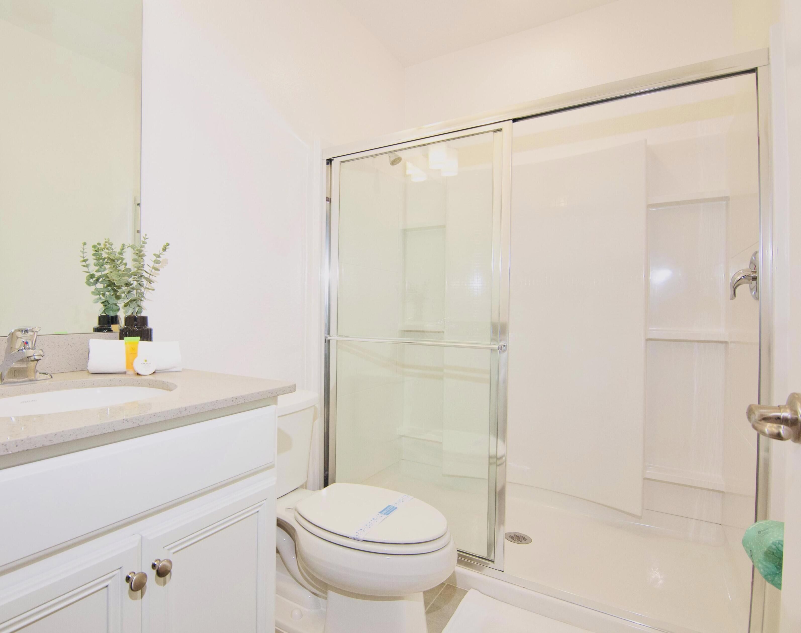 A bathroom with a glass shower enclosure, a white sink, and a toilet.