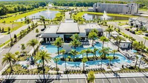 Un hôtel doté d’une piscine centrale, de palmiers et d’un parking.