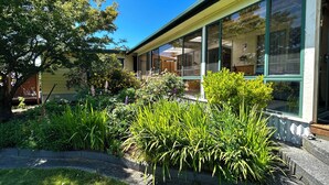 A modern house with large windows, a well-maintained garden, and a clear blue sky. - Hamlet Downs Country Accom (Fentonbury)