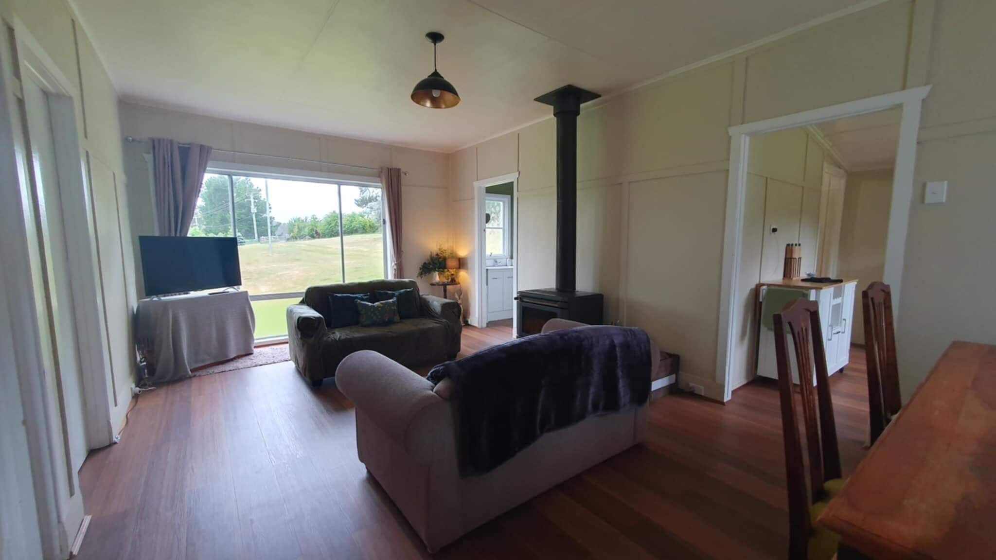 A spacious living room with a sofa, a television, and a fireplace.