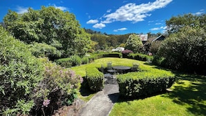 A well-maintained garden with a paved path leading to a seating area with chairs and a table. - Hamlet Downs Country Accom (Fentonbury)