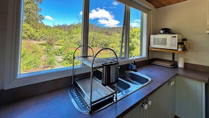A kitchen with a large window, a sink, a microwave, and a metal rack. - Hamlet Downs Country Accom (Fentonbury)