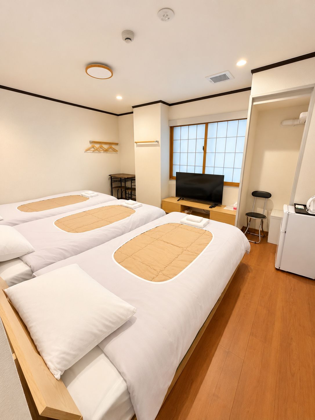 A hotel room with two beds, a TV, a desk, and a window.