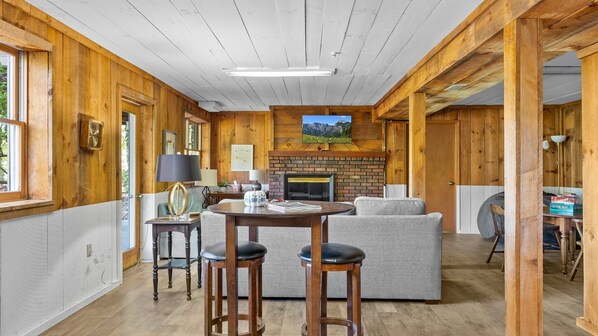 Ein gemütliches Blockhaus-Interieur mit Kamin, Holzwänden, einer Essecke und einer Couch.