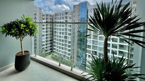 A balcony with a view of high-rise buildings, potted plants, and a clear sky. - CELEDON Tân Phú (Ho Chi Minh City)