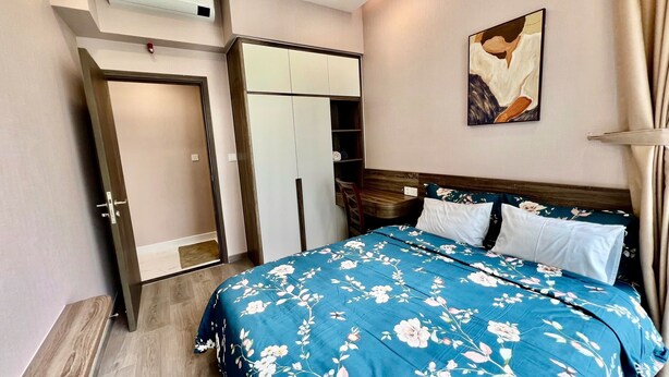 Een slaapkamer met een bed, een kledingkast, een bureau en een schilderij aan de muur.