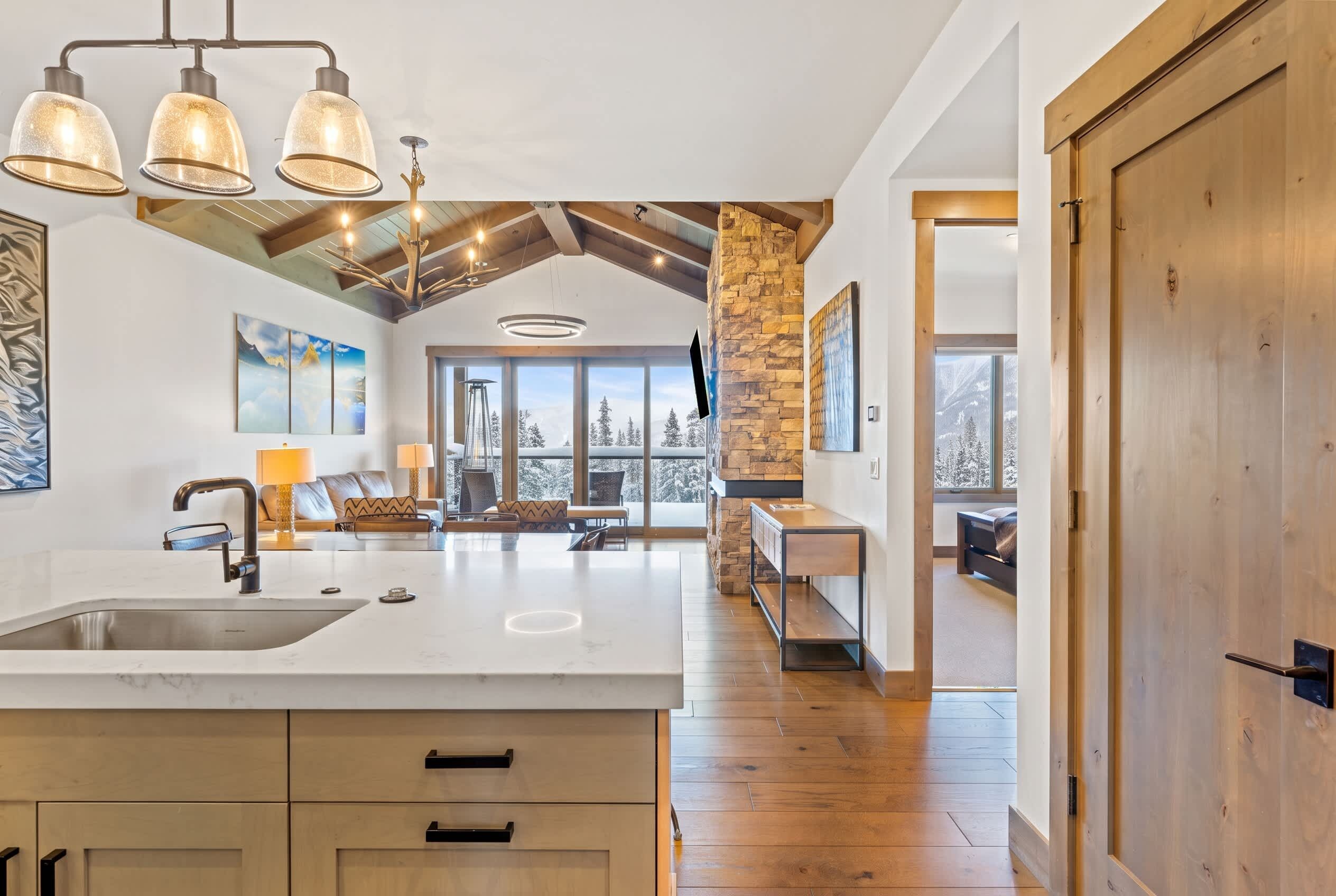 A spacious kitchen with a large island, wooden beams, and a stone accent wall.