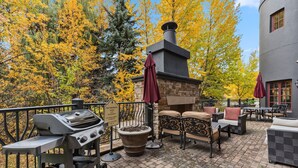 Un patio al aire libre con una parrilla, zona de estar y una chimenea.