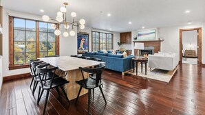 Amplia sala de estar con una gran mesa de comedor, sofá azul y chimenea.